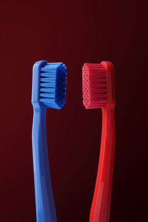 Two plastic toothbrushes red and blue on a dark red background. Oral hygiene. Morning routine.の写真素材