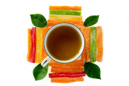 Cup of tea with pineapple candied fruits and green leaves on a white backgroundの写真素材