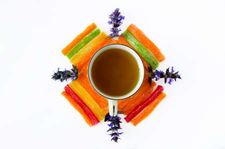 Cup of tea with pineapple candied fruits and blue field flowers on a white backgroundの写真素材