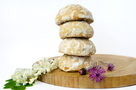 White cookies on a wooden board decorated with field flowers and a branch of acaciaの写真素材
