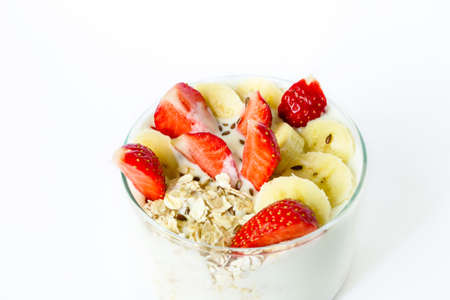 Homemade yogurt with oat flakes strawberry and banana and flax seeds in a glass beaker on a white backgroundの写真素材
