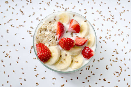 Homemade yogurt with strawberry, banana, oat flakes, flax seeds on a white background sprinkled with flax seeds. Top viewの写真素材