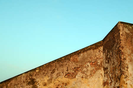Old concrete wall of brown color against the blue sky. The geometry of the building. Abstract architecture.の写真素材