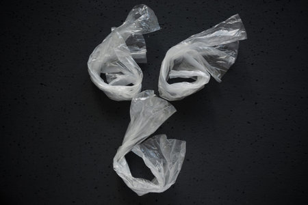 Face laid out of empty plastic bags on a dark background. The concept of consumption and pollution...