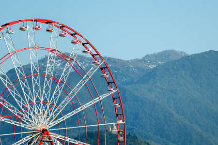 Part of the Ferris wheel against the backdrop of the mountains covered with forests.の写真素材