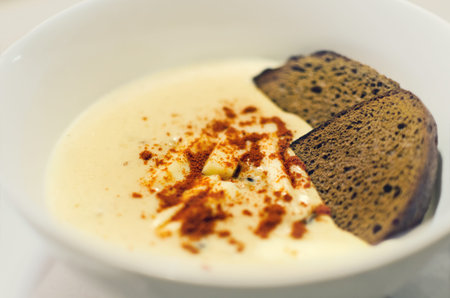 Cream soup sprinkled with paprika with rye bread in a white plateの写真素材