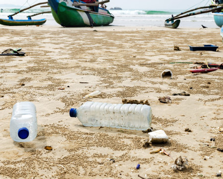 Empty used plastic bottles and other waste thrown out at the sea beach on background is fishing...