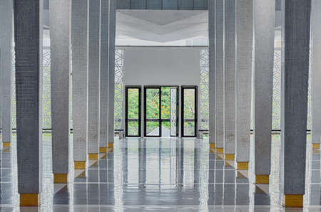 Long corridor between many columns, open doors in the end, symmetric modern hall in National Mosque (Masjid Negara), Kuala Lumpur, Malaysia. Functional interior with natural ventilation and lighting.のeditorial素材