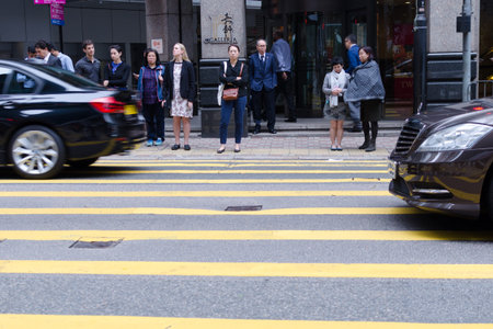 Hong Kong, 2018-03-06: People waiting to cross street, pedestrian crossing on busy road, city daily...