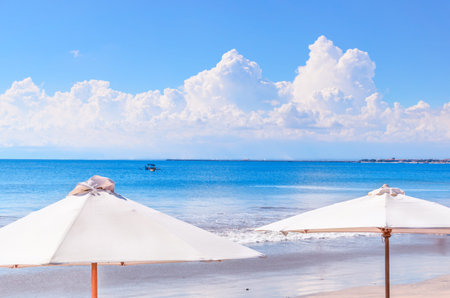 Beach umbrellas at calm blue sea backdrop. Concept of an ideal tropic exotic vacation. Summer sea landscape. Beach view wallpaper. Bali island.の写真素材