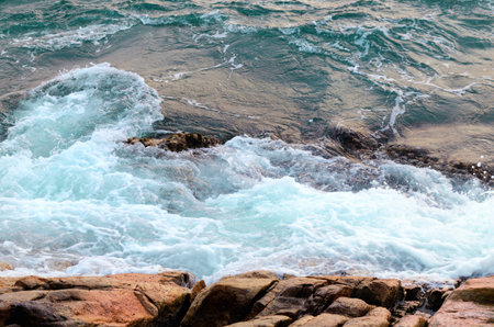 Foaming sea water hits stone beach, wave and beach, nature background concept. Photo with motion...
