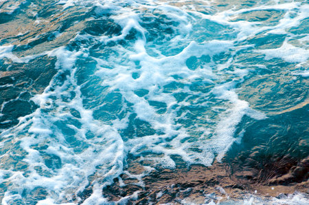 Foamy water waves at the ocean, view from above. Top view sea texture. Photo with motion blur.