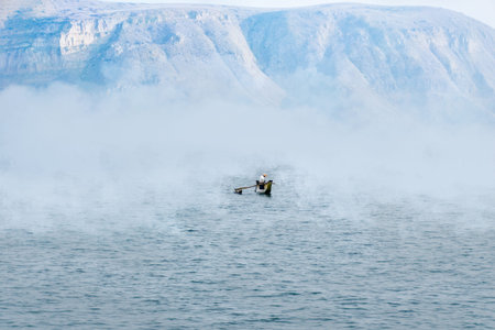 Foggy morning, a fisherman in a boat on the lake. Nature loneliness, solitude.の写真素材