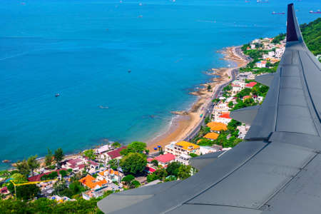 Beautiful view from the plane on the resort town by the sea Vung Tau, Vietnam. Resort town in the tropics.  Landscape with hills, sea, and cozy city in greensの写真素材