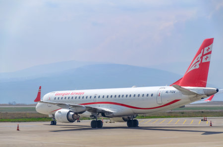 Georgian Airlines plane at the airport on a background of mountains. Georgia, Tbilisi, 2019-04-10
