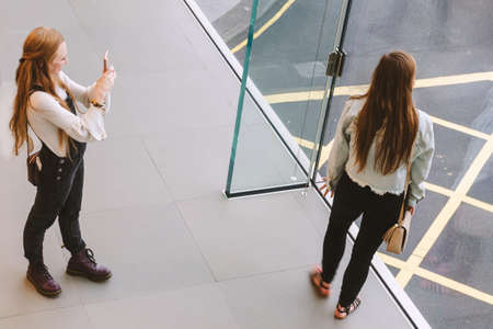 Woman photographs her friend on the phone. View from above. Hong Kong, 2018-03-14のeditorial素材