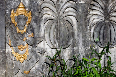 Figure of a man in a golden headdress carved in the wall.  Ancient wall decor, Bali, Indonesia.の写真素材