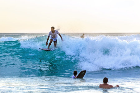 Surfer catches a turquoise wave in the backlight. Active water sports concept. Photo with blur in...