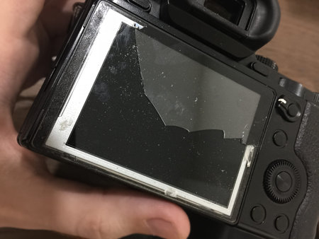 Camera with broken glass on the display in the hands of the repairer
