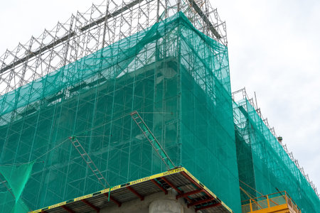 Corner of the facade of the building under construction is covered with a protective construction...