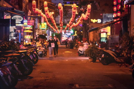 Two unrecognizable  women in mask on the night street. Blurred asian alley street with chinese...