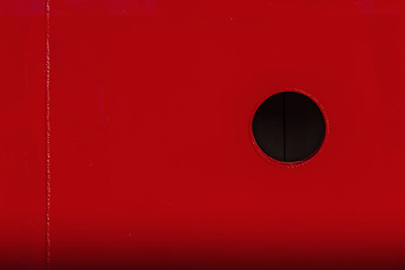Red metal gradient background with black circle porthole.  Empty place for text, copy space.