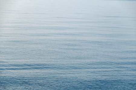 Calm Water Surface. Textured sea water with fine ripples.  Ocean merges into the sky.  Defocused photo with blur in motion.の写真素材