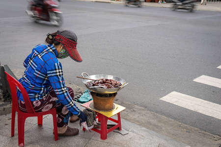Asian woman cooking traditional snack by the city road.  Fried bananas in syrup, Â exotic food traveling. Nha Trang, Vietnam.の写真素材