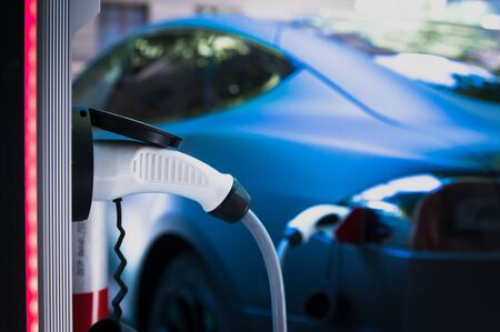 Charging modern electric car with cable plug inserted ir public parking lotの写真素材