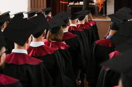 Group of fresh university graduates with robes and caps in ceremonyの写真素材