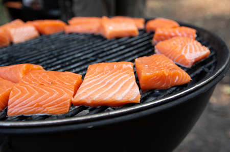 Pieces of raw pink salmon cooking on grillの写真素材