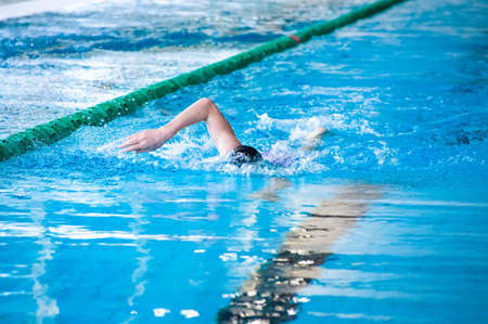 Swimming person in comptetition doing freestyle stroke with one hand over waterの写真素材