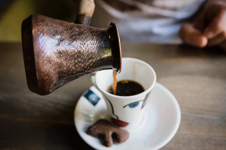 Person hands pouring traditional turkish coffee into a cup during an eastern traditional drinking ceremonyの写真素材