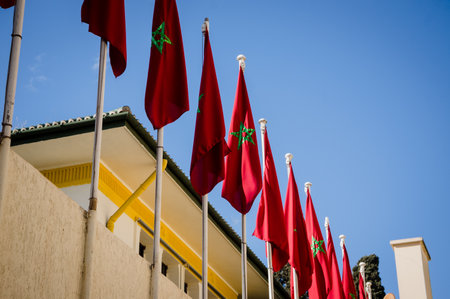Multiple red flags of Morocco waving in the wind against blue sky background outsideの写真素材