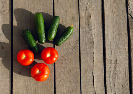 tomatoes with cucumbers lie on a wooden tableの写真素材