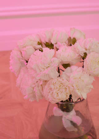 white wedding bouquet of roses in a vase in pink lighting with a place for a signatureの写真素材