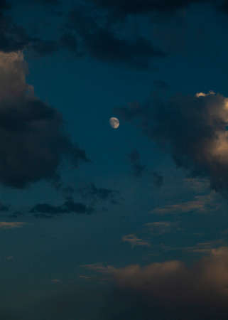 sunset with dark clouds and a bright moonの写真素材