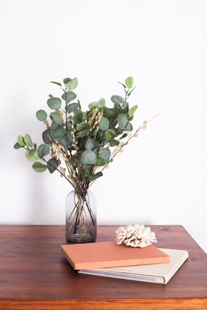 a bouquet of plants in a vase stands on a table in a minimalistic interior with a white tableclothの写真素材