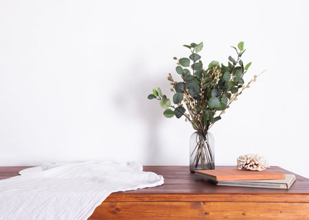 a bouquet of plants in a vase stands on a table in a minimalistic interior with a white tableclothの写真素材