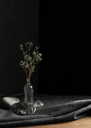 dark still life with white flowers dried flowers and a glass bottleの写真素材