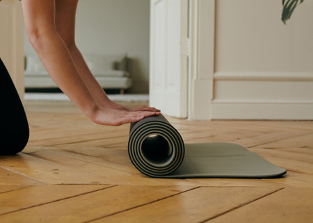 a woman rolls out a yoga mat at homeの写真素材