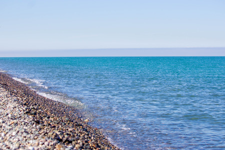 Natural concept. Blue sea, sea coast, small stones. Summer sunny day. Waves in the sea.の写真素材