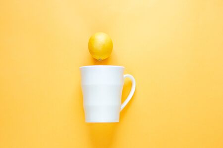 Flat layout. Mug and lemon on a yellow background.の写真素材