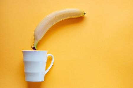 Banana lies with a mug on a yellow background. Flat layout.の写真素材