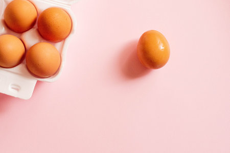 Eggs in a white box and egg on a pink background. A background with a place for text for the Easter...