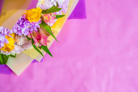 Bright bouquet of flowers on a pink background. There is space for text. Flat lay photo from above.の写真素材