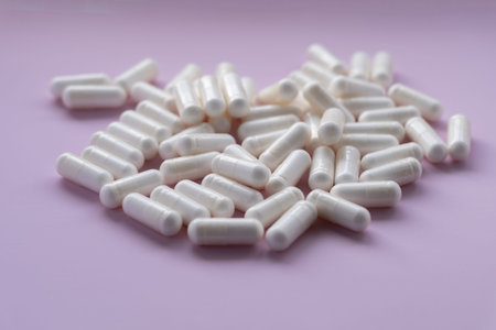 White capsules on a pink background. Dietary supplement in capsules on a pink background.