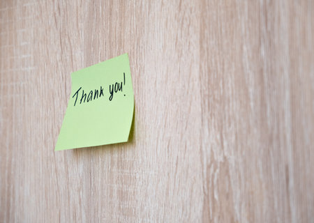 Sticker with the inscription thank you on a wooden wall. Day Thank you.の写真素材