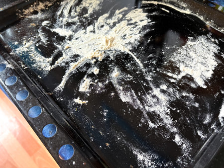 a dark baking sheet covered with flour, dough scraps, and flour dust from making bread or baking.の写真素材