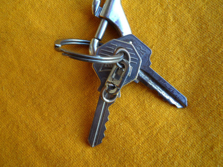 Two keys on a metal keholder over yellow background